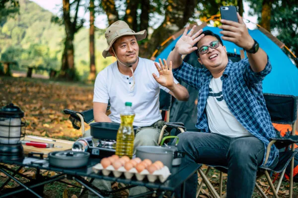 portrait happy asian man friends making video call with smartphone camping cooking set front ground outdoor cooking traveling camping lifestyle concept